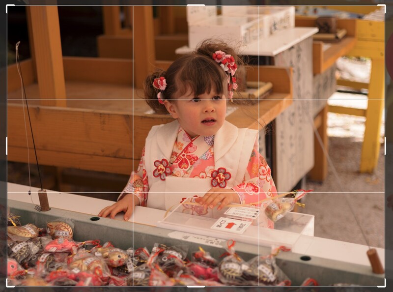 Young child in pink floral dress examining items in a glass display case.
