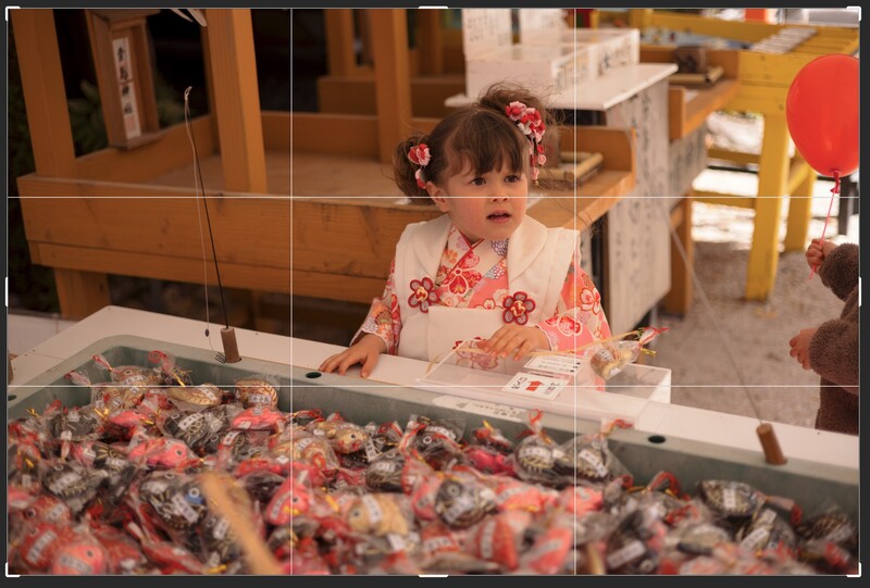 Young child in pink floral dress examining items in a display case at what appears to be a museum or shop.