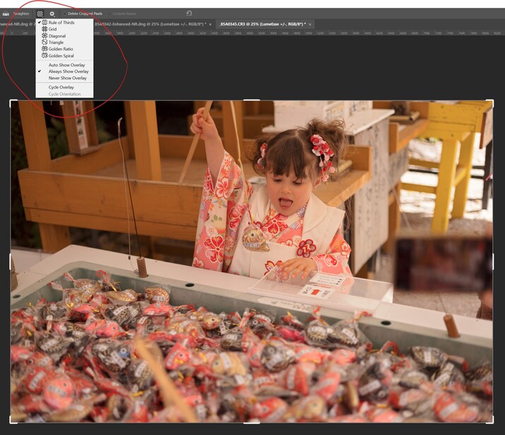 Young child in floral dress reaching over display case of baked goods in wooden-framed shop interior.