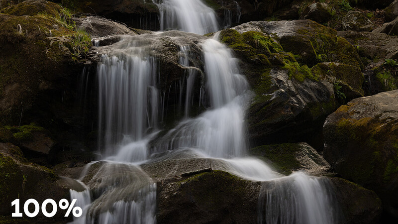 Multi-tiered waterfall cascading over moss-covered rocks with long exposure blur effect