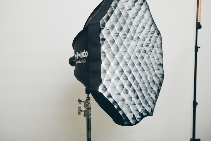 Octagonal softbox with white diffusion fabric mounted on studio light stand against white wall.