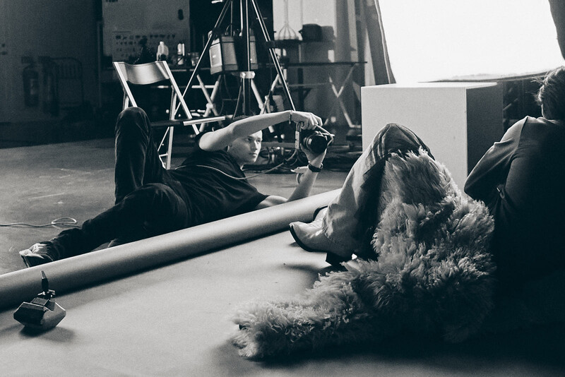 Studio setup with lighting rig and person lying on floor with fabric prop during photography session.
