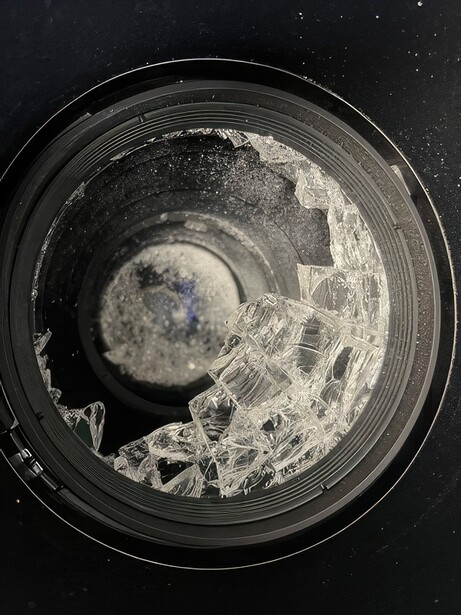 Lunar surface photograph through telescope eyepiece showing craters and surface texture in high detail.