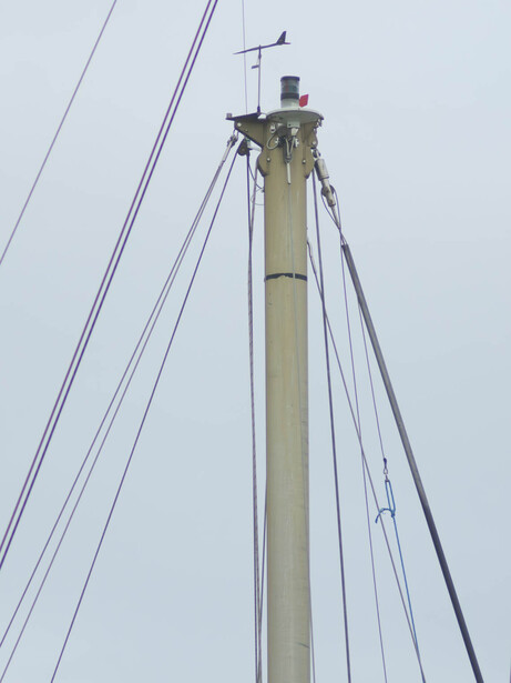 Tall concrete utility pole with multiple guy wires against overcast sky.