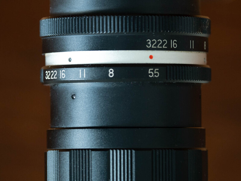 Close-up of vintage lens barrel showing focus and aperture rings with engraved markings and numbers.