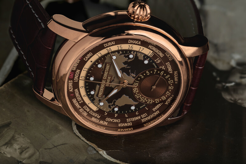 Rose gold luxury watch with world time dial and dark leather strap displayed on gray surface.