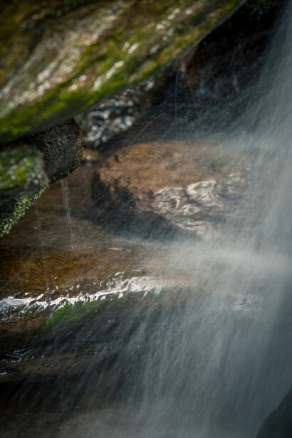 Smooth water cascades over moss-covered rocks in a flowing stream.