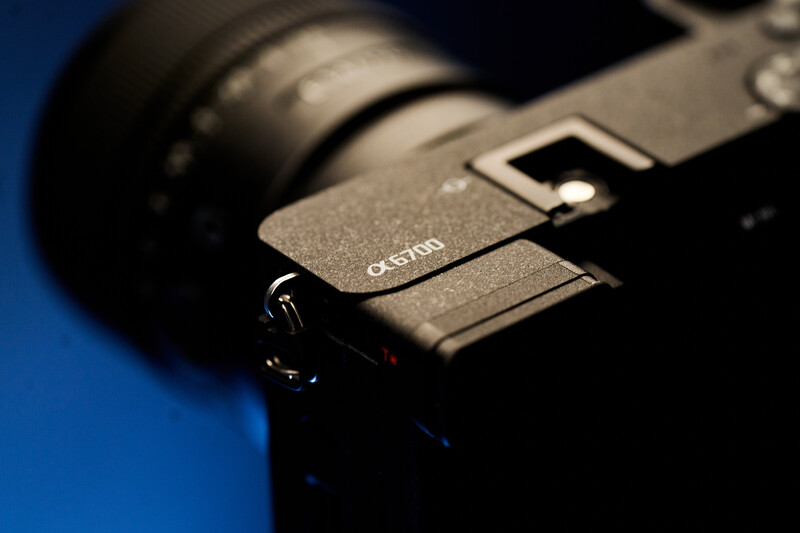 Close-up of a camera body showing the Canon branding and grip area against a blue background.