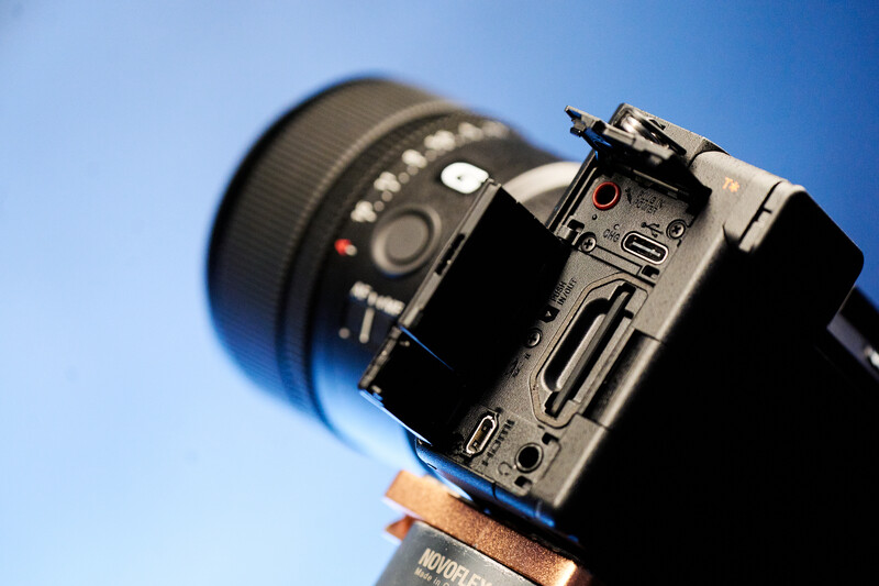Professional video camera mounted on wooden support against clear blue sky.