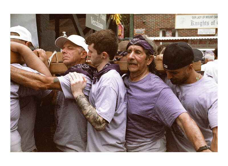 Group of men in casual wear huddled together in a tight cluster outdoors.