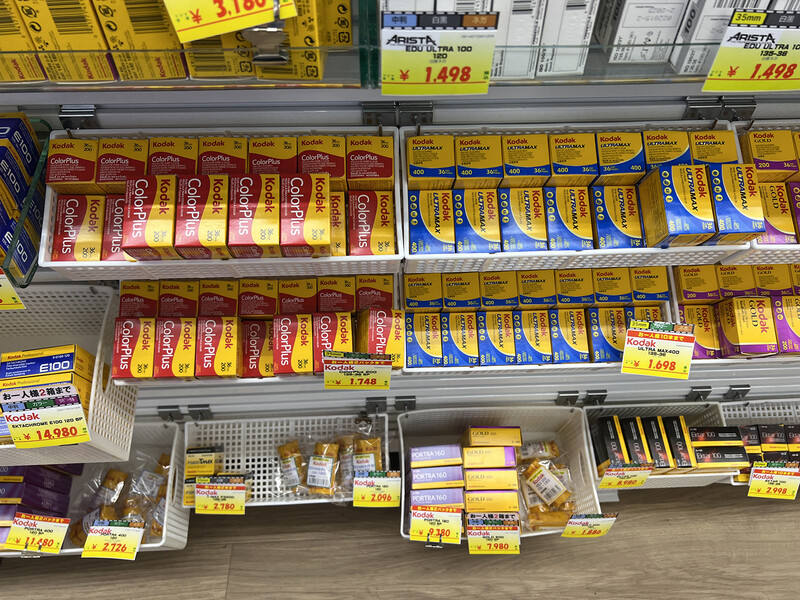 Supermarket shelf display with packaged food products arranged in rows, featuring red and yellow branded boxes on upper shelves and blue boxes below.