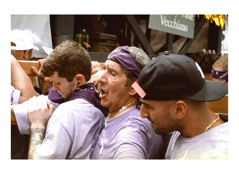Group of people wearing purple headbands and casual clothing in a crowded outdoor setting.