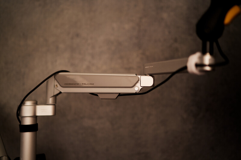 Close-up of a camera articulating arm with ball head and quick-release plate mounted on tripod.