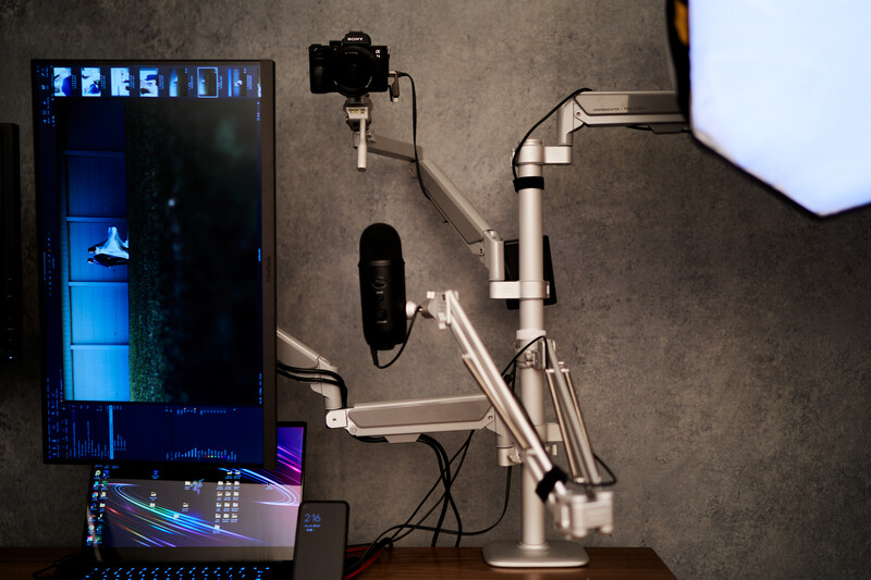 Overhead view of a content creator's streaming setup with monitor, microphone arm, and laptop on desk.