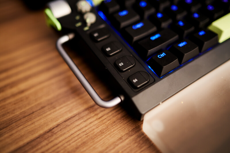 Mechanical keyboard with blue backlighting and white mouse on wooden desk surface.