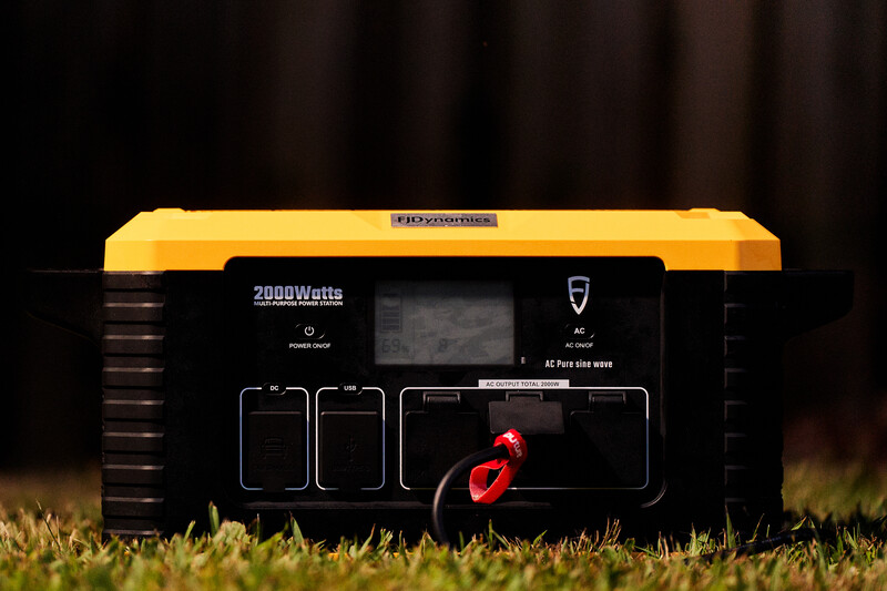 Yellow and black portable power station with 2000W capacity displayed on grass at dusk.