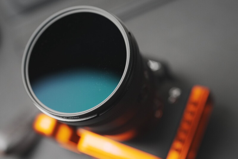 Open paint can filled with turquoise liquid, shot from above with blurred orange and yellow elements in the background.