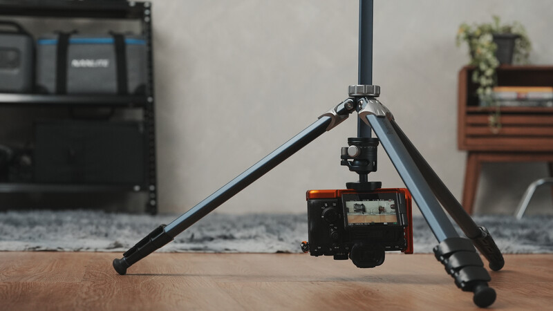 Compact mirrorless camera mounted on a small tripod with extended legs in a studio setting.
