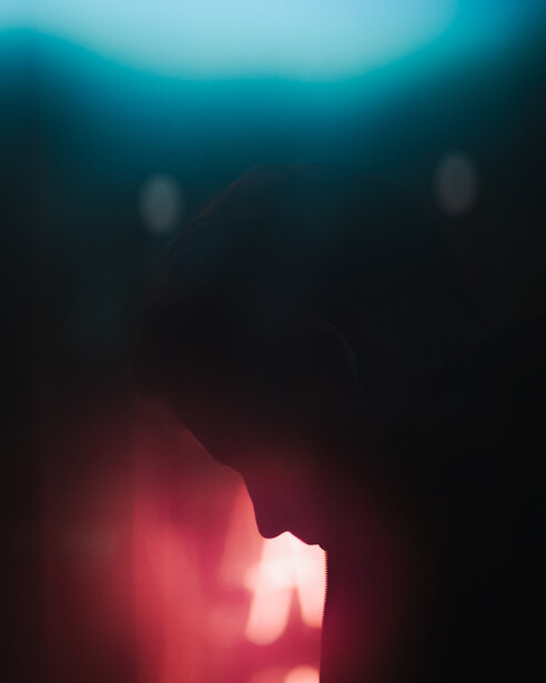 A partial silhouette shows part of a face surrounded by colourful light