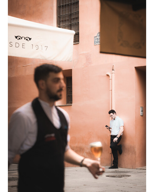 One member of bar staff takes a break while the other brings a customer their next beer