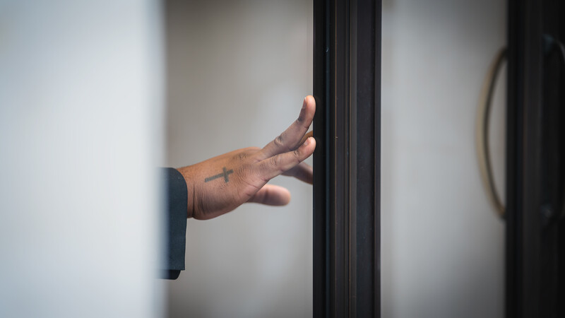 Stretched fingertips gently push a door frame