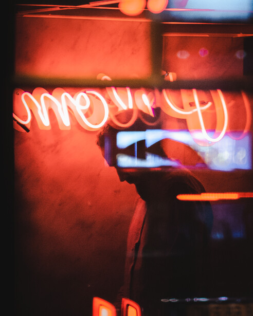 Layers of red and blue light surround the silhouette of a man