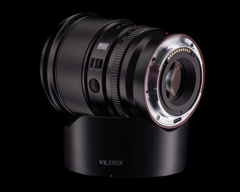 Viltrox lens mounted on black cylindrical lens hood, photographed against dark background.