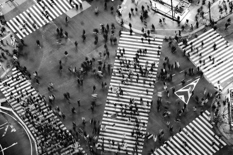 Aerial view of multiple zebra crossings with pedestrians scattered across intersections and walkways.