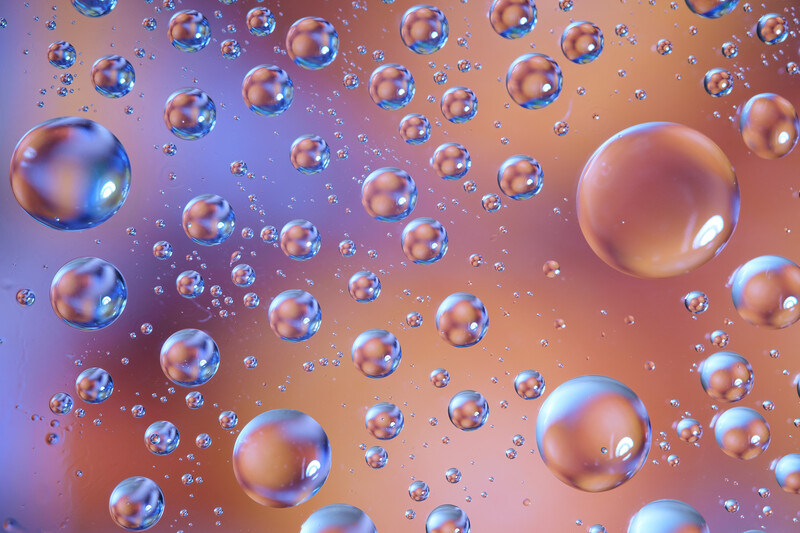 Floating soap bubbles of varying sizes against a gradient background transitioning from purple to orange.
