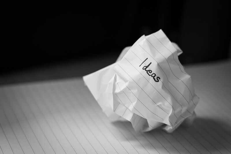 Crumpled paper with handwritten text on lined notebook paper against dark background.