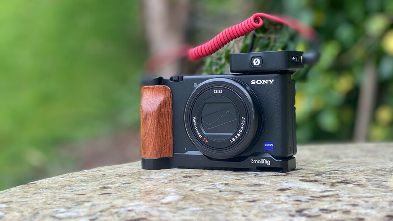 Sony camera with wooden grip and red microphone mounted on a concrete surface outdoors.