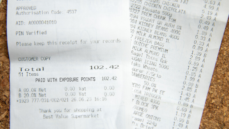 Supermarket receipt showing itemized grocery purchases totaling 102.42 with exposure points reward notation.