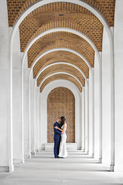 Person standing in a symmetrical archway corridor with white columns and exposed brick vaults.