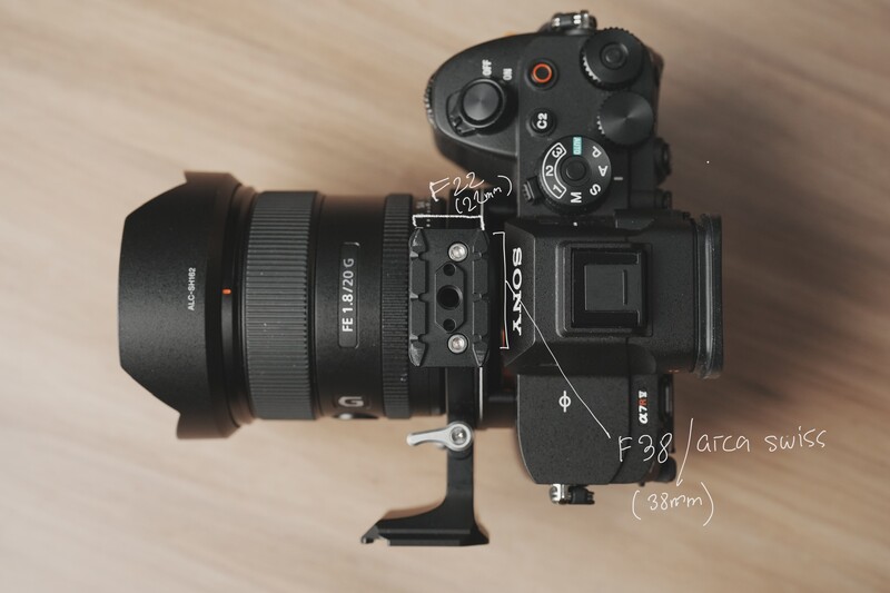 Black mirrorless camera with wide-angle lens and wireless transmitter mounted on wooden surface.
