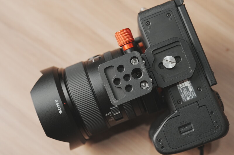Camera lens mounted on smartphone holder with orange adjustment knob visible.