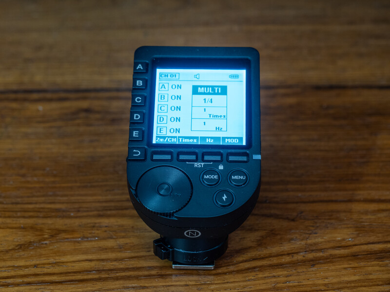 Flash trigger transmitter displaying channel and power settings on LCD screen.