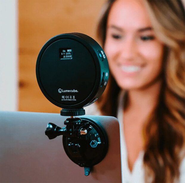 Spherical LED ring light mounted on camera with woman blurred in background.