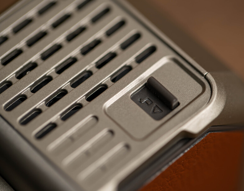 Close-up of a ventilated electronic device with perforated grilles and a control button.