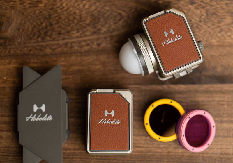 Flat lay of photography gear including lens filters, carrying case, and branded accessories arranged on wooden surface.