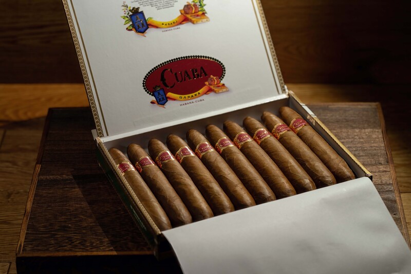 Open box of premium cigars arranged in rows with decorative band labels visible.