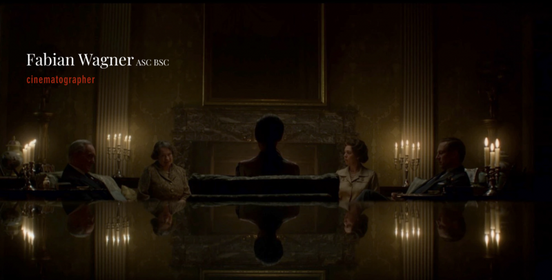 Five people seated around a reflective table in an ornate hall with classical columns and candlelit wall sconces.