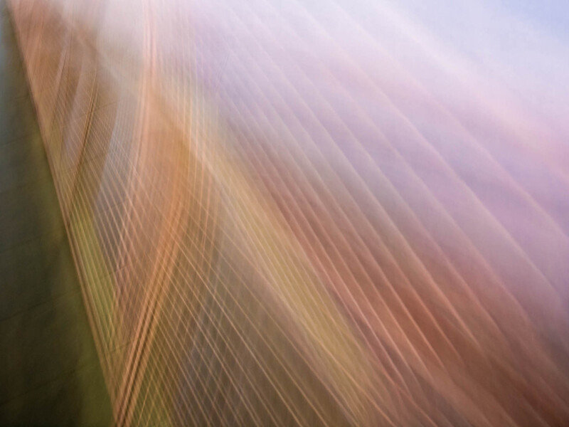 Abstract image with diagonal linear patterns blending warm orange and peachy tones into cool purples and blues.