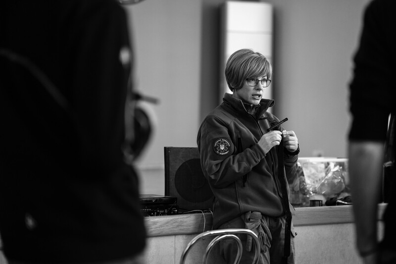 Young person speaking at microphone during indoor event, captured in black and white photography.