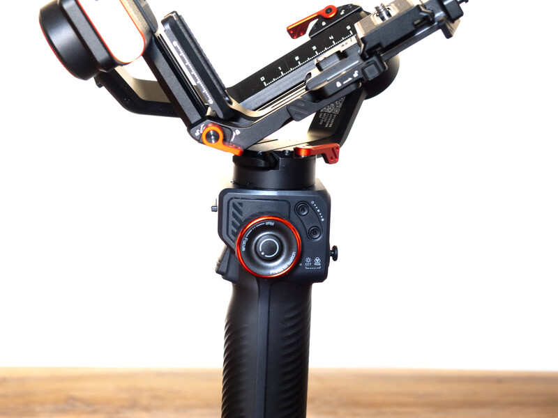 Three-axis gimbal stabilizer with mounted camera and smartphone holder against neutral background.