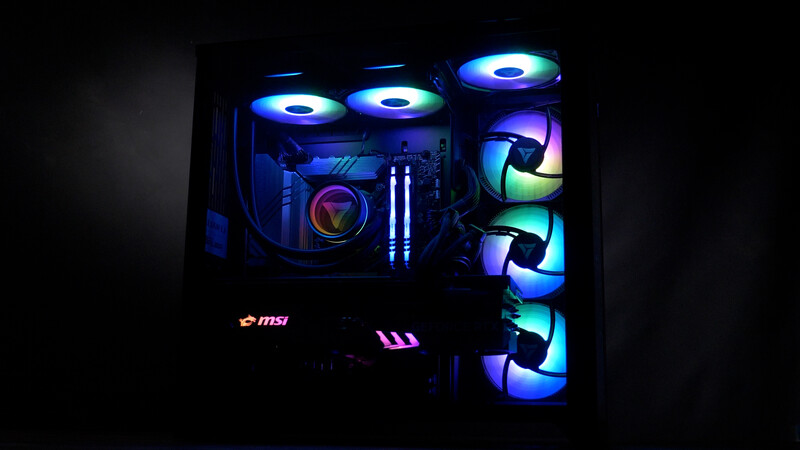 Custom-built gaming PC with RGB-lit cooling fans and components illuminated in blue and purple tones.