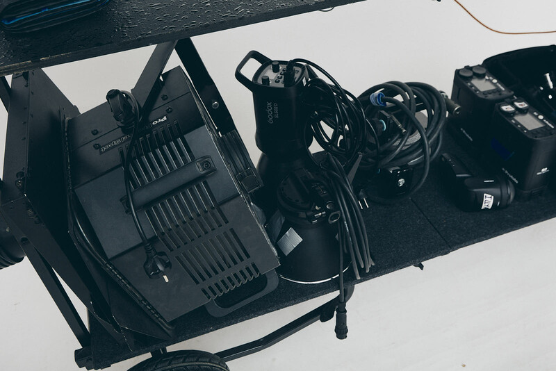 Professional lighting equipment laid out on white surface, including a large monolight and various cables and accessories.