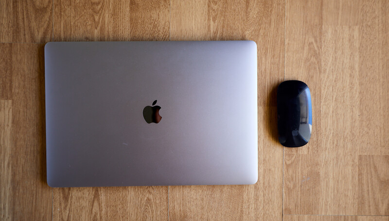 MacBook and wireless mouse on wooden floor.