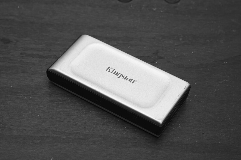 Kingston portable external SSD in white and black, photographed from above on a dark textured surface.