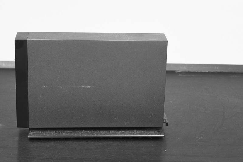 Gray rectangular box positioned on dark surface against neutral background with dramatic side lighting.