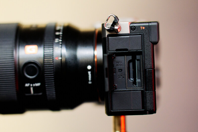 Compact mirrorless camera with attached lens shown from the right side against a neutral background.